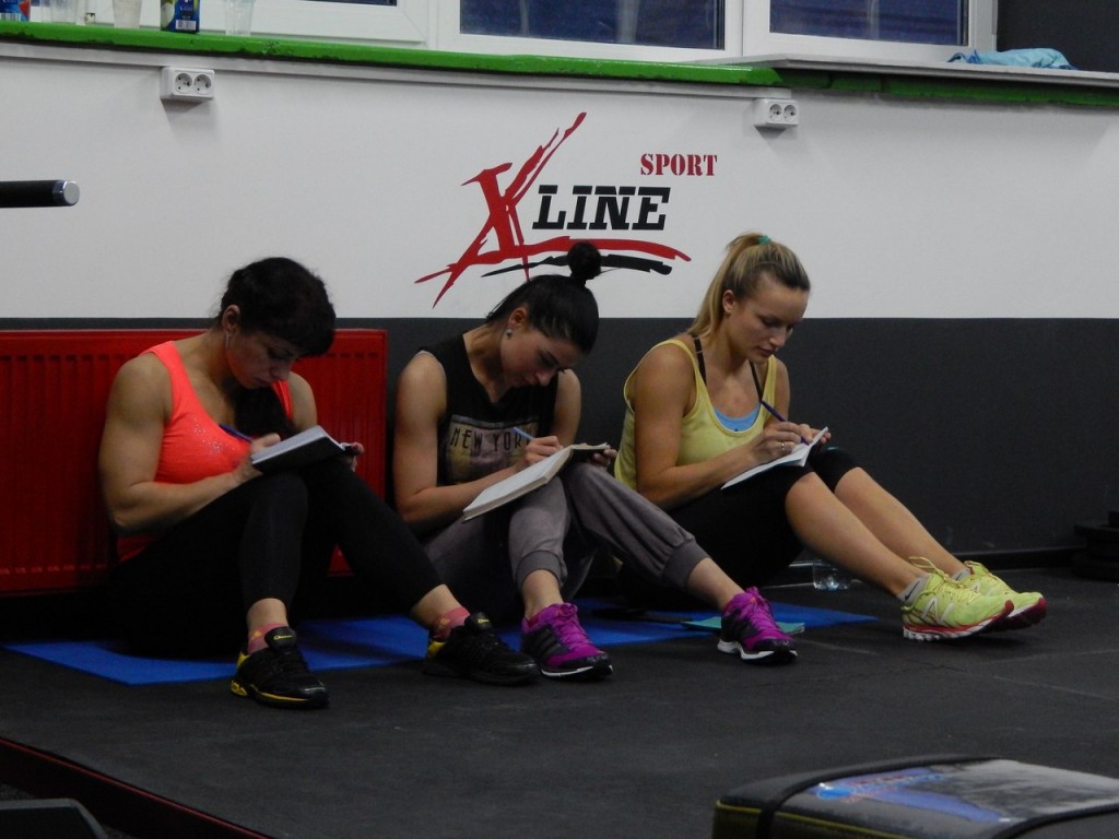 девушки записывают свои упражнения в дневник тренировок